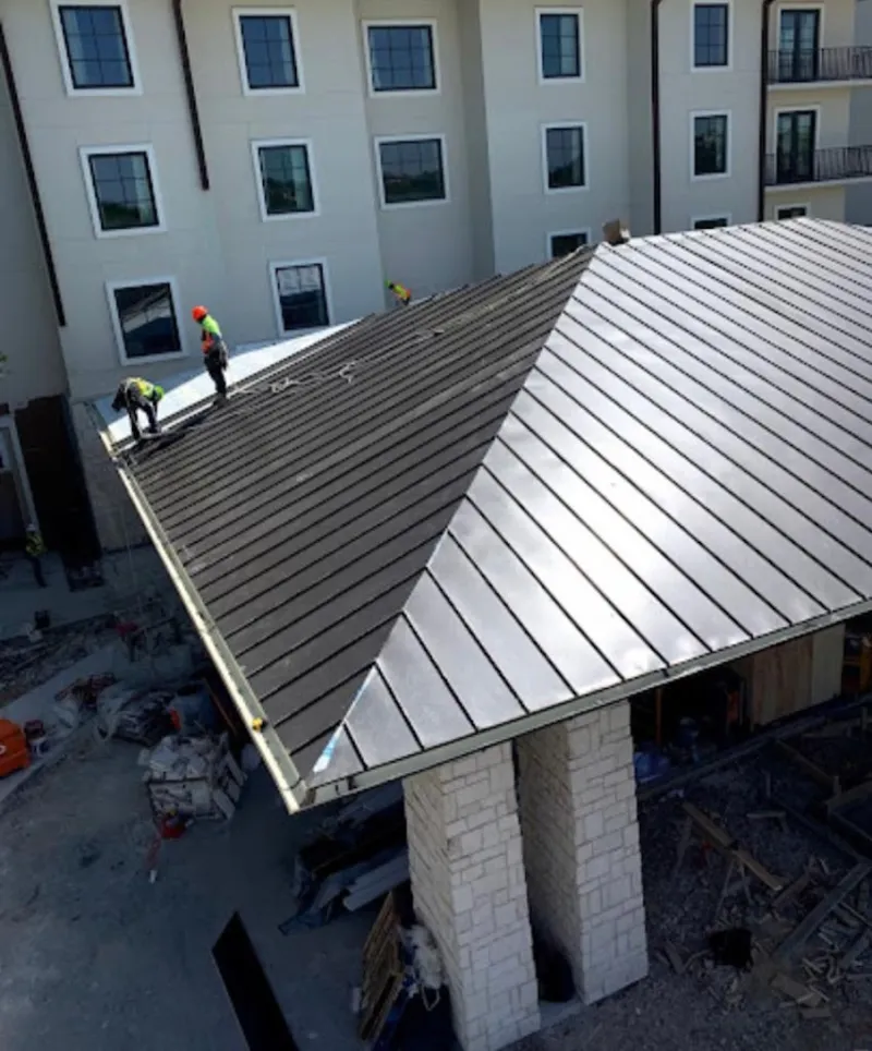 Crew installing standing seam metal roof panels on a commercial project in Warren